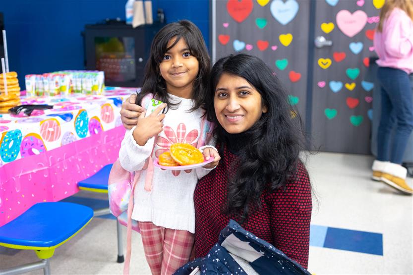 Creekside Elementary students eat donuts with a grown-up